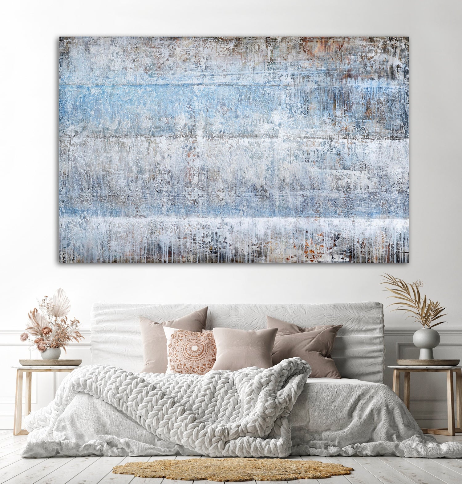 Abstract blue and gray oversized wall art above a cozy, neutral-toned bedroom with decorative pillows and a blanket.